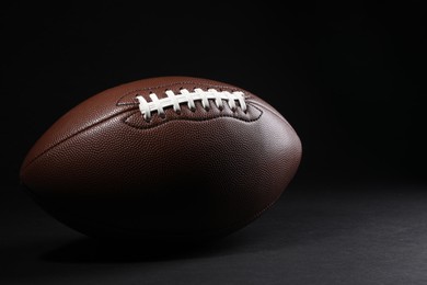 Photo of American football ball on black background. Space for text