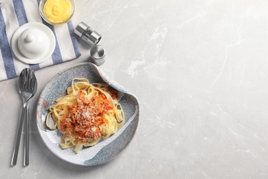 Plate with delicious pasta bolognese on light background, top view