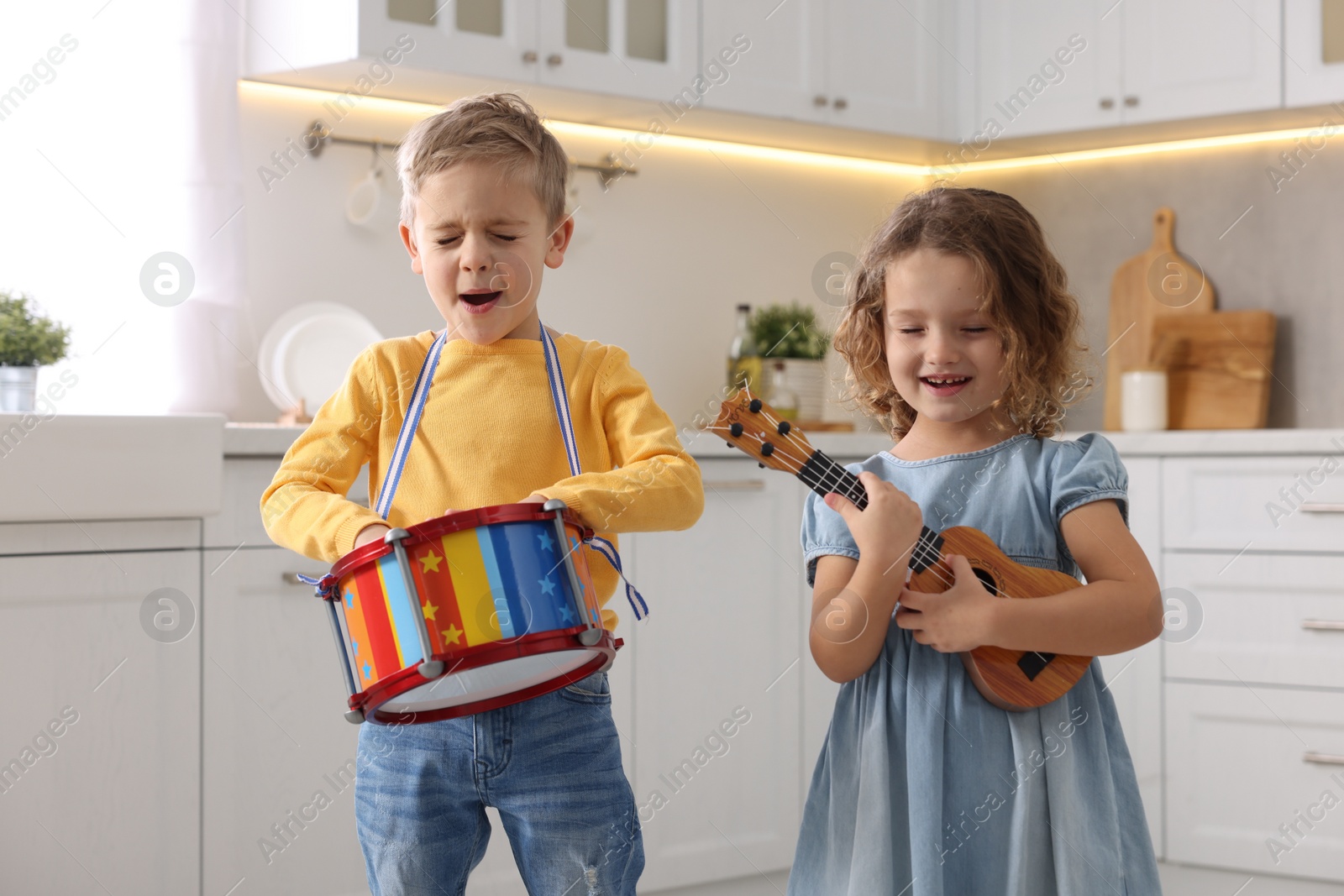 Photo of Little children playing toy musical instruments in kitchen