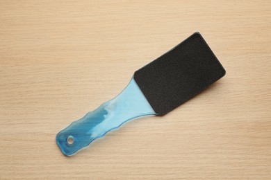 Blue foot file on wooden table, top view. Pedicure tool