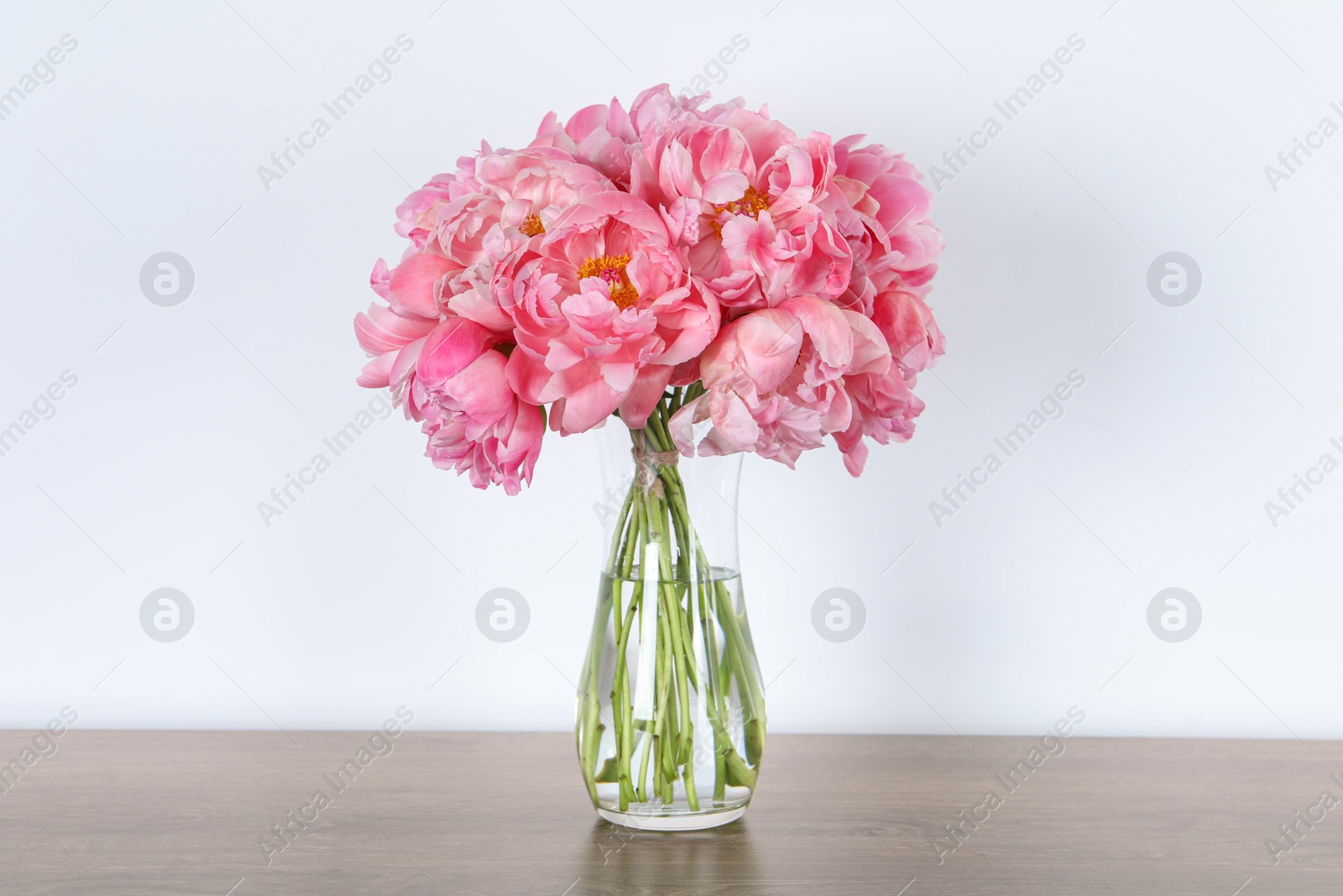 Photo of Beautiful bouquet of pink peonies in vase on wooden table against white background