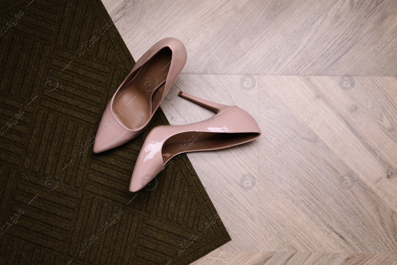 Photo of Stylish door mat and shoes on wooden floor, top view