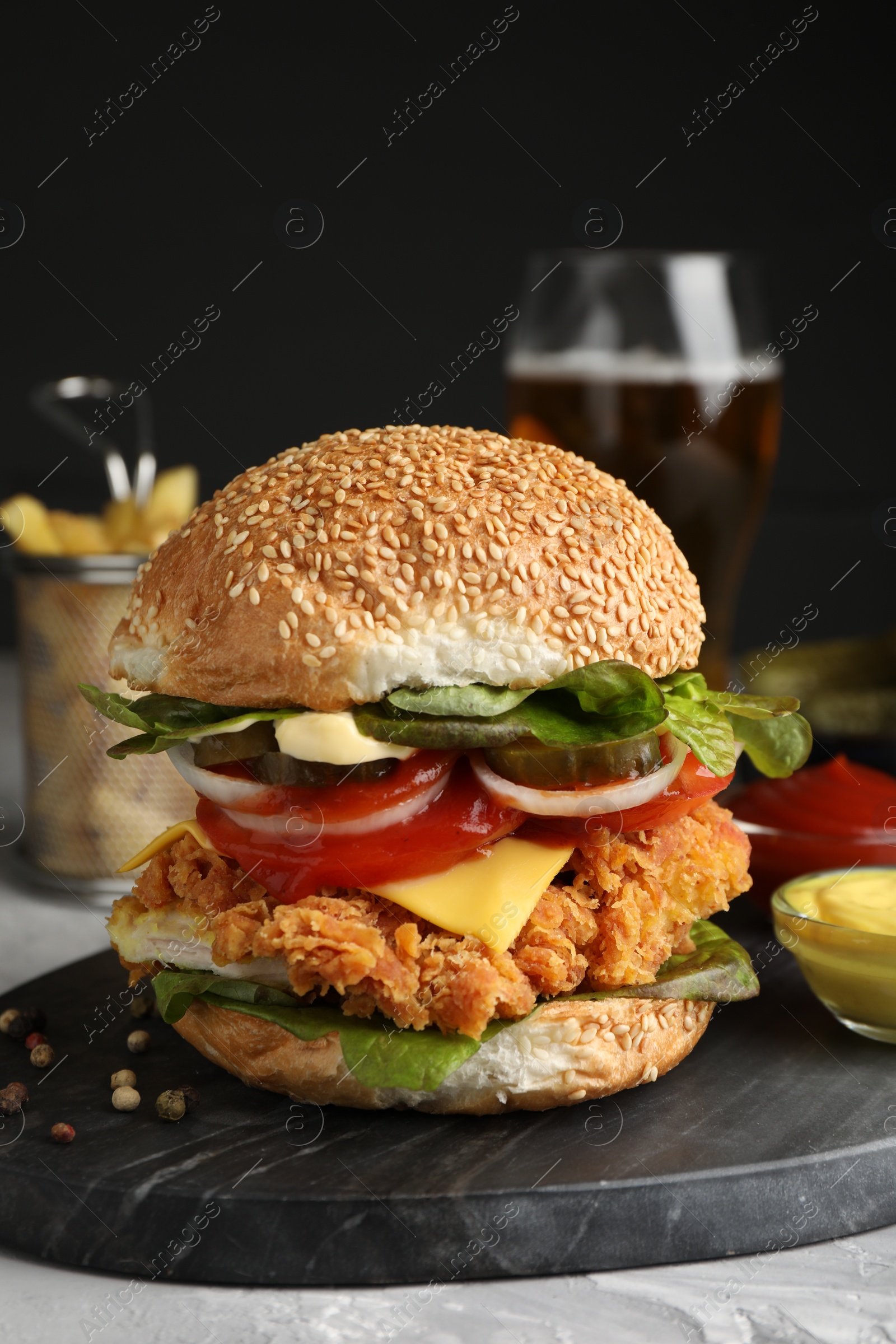 Photo of Delicious burger with crispy chicken patty and sauces on grey table, closeup