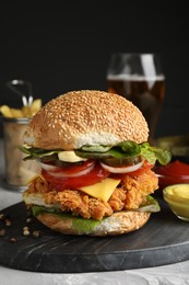 Delicious burger with crispy chicken patty and sauces on grey table, closeup