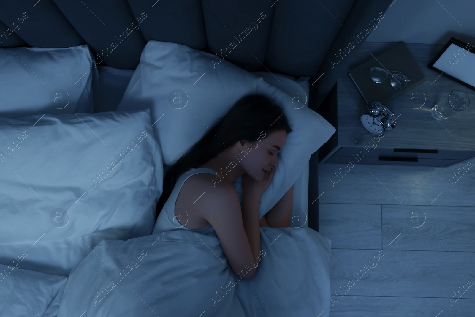 Photo of Beautiful young woman sleeping in bed at night, top view