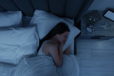 Photo of Beautiful young woman sleeping in bed at night, top view