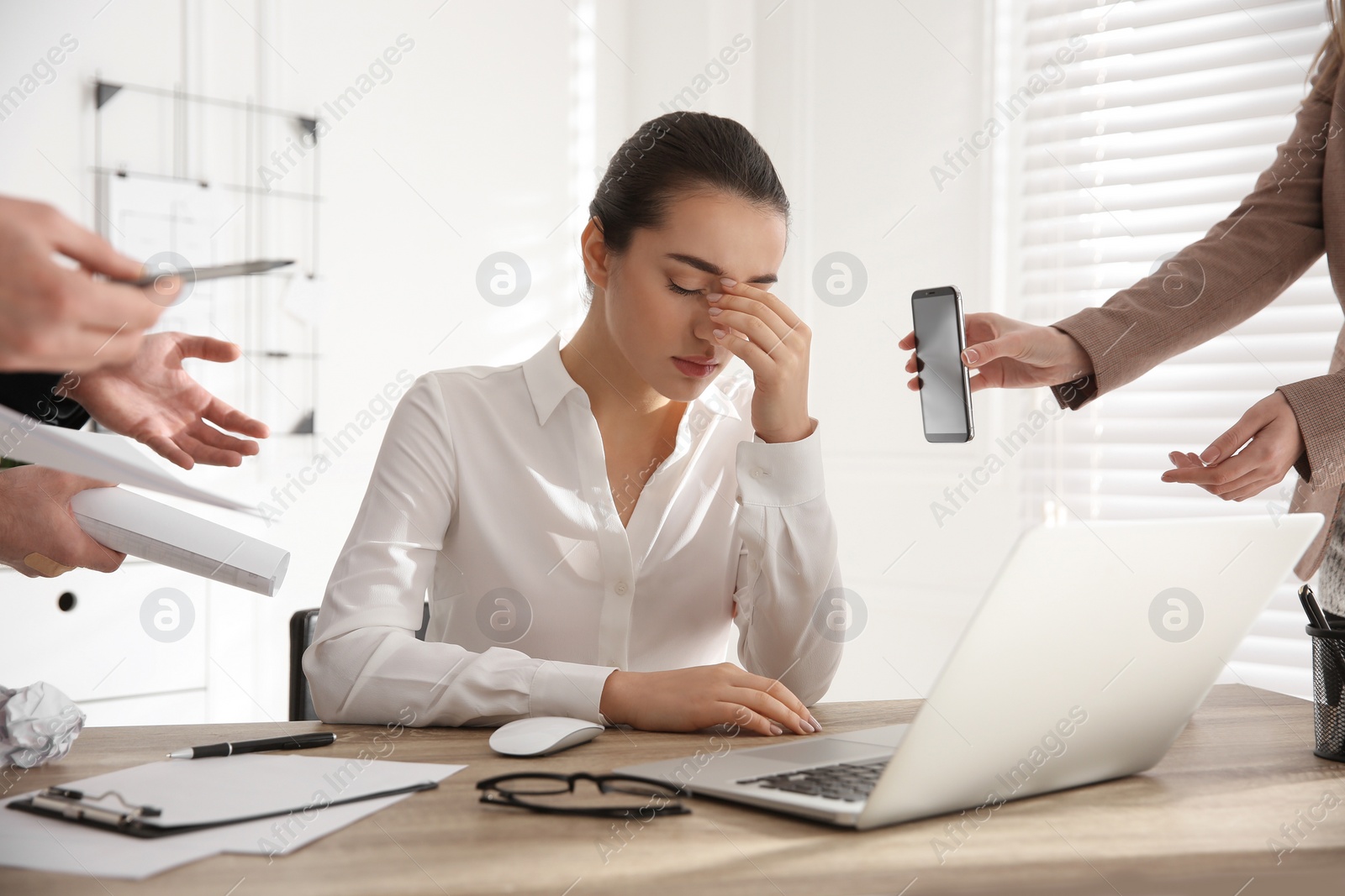Photo of Stressed and tired young woman surrounded by colleagues at workplace, closeup