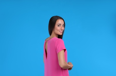 Photo of Young woman wearing pink dress on light blue background