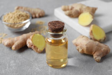 Glass bottle of essential oil and ginger root on grey table