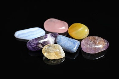 Pile of different beautiful gemstones on black background