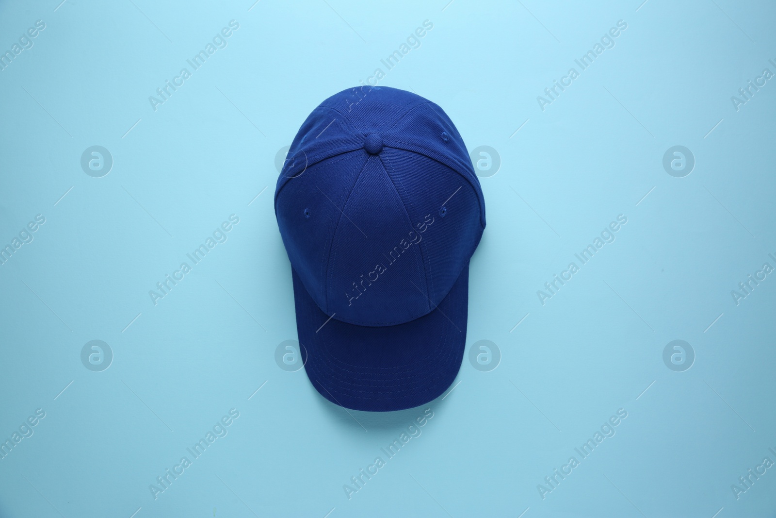 Photo of Stylish baseball cap on light blue background, top view