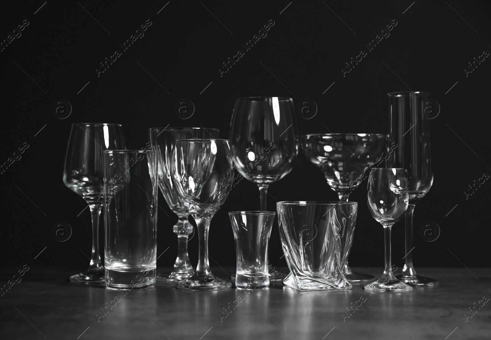 Photo of Set of bar glassware on table against dark background