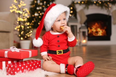 Photo of Baby in Santa hat with Christmas gift at home