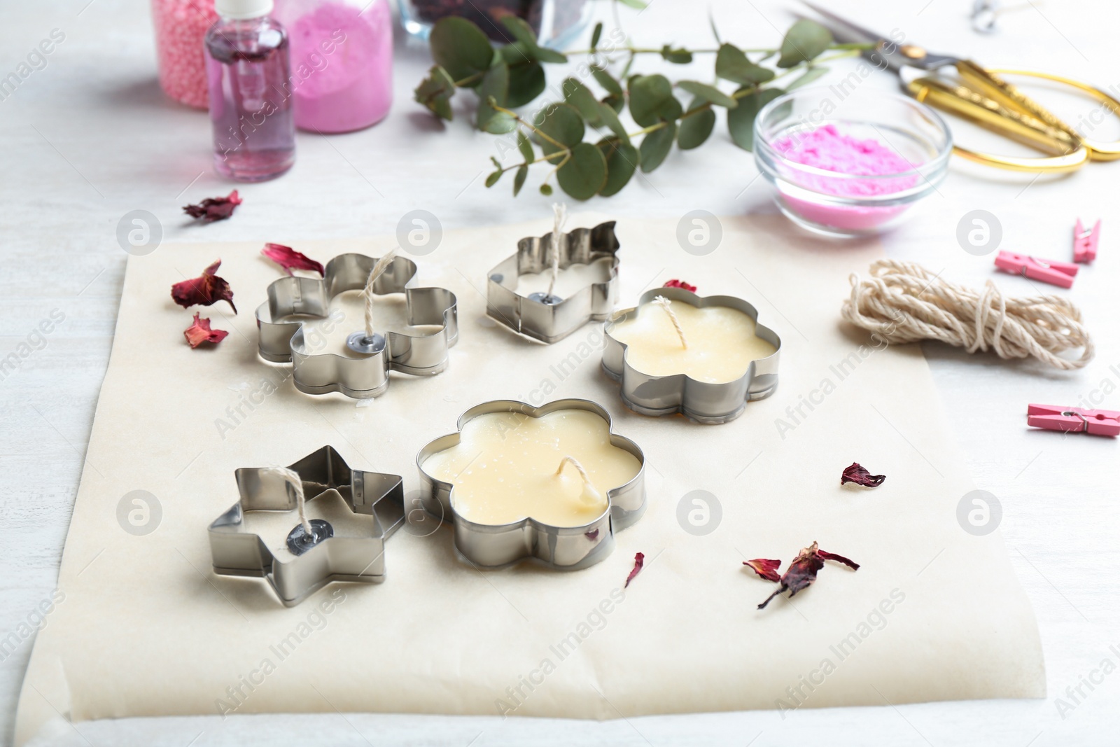 Photo of Handmade candles with cutters and paper on table