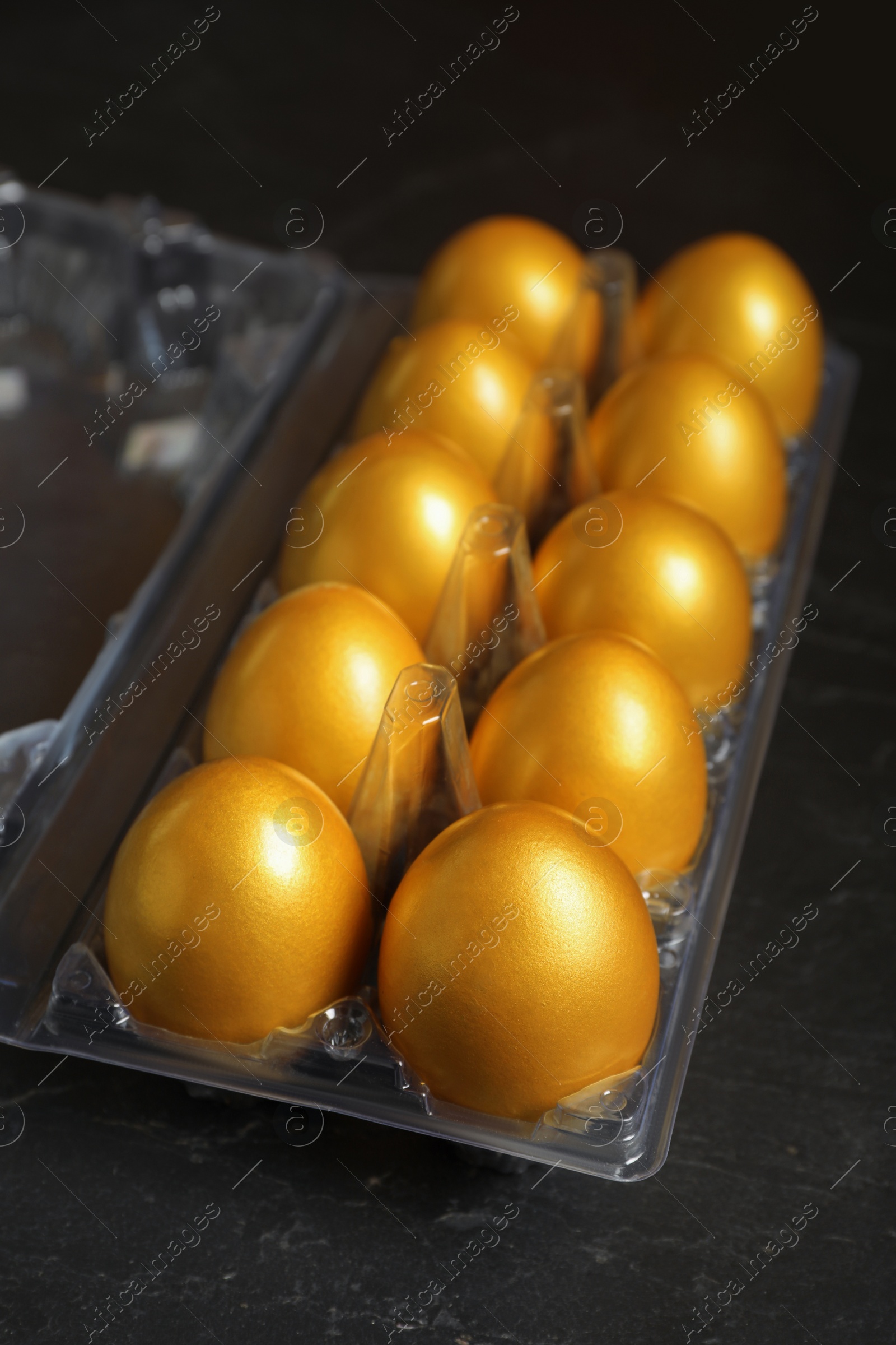 Photo of Shiny golden eggs in plastic box on black table