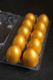 Photo of Shiny golden eggs in plastic box on black table