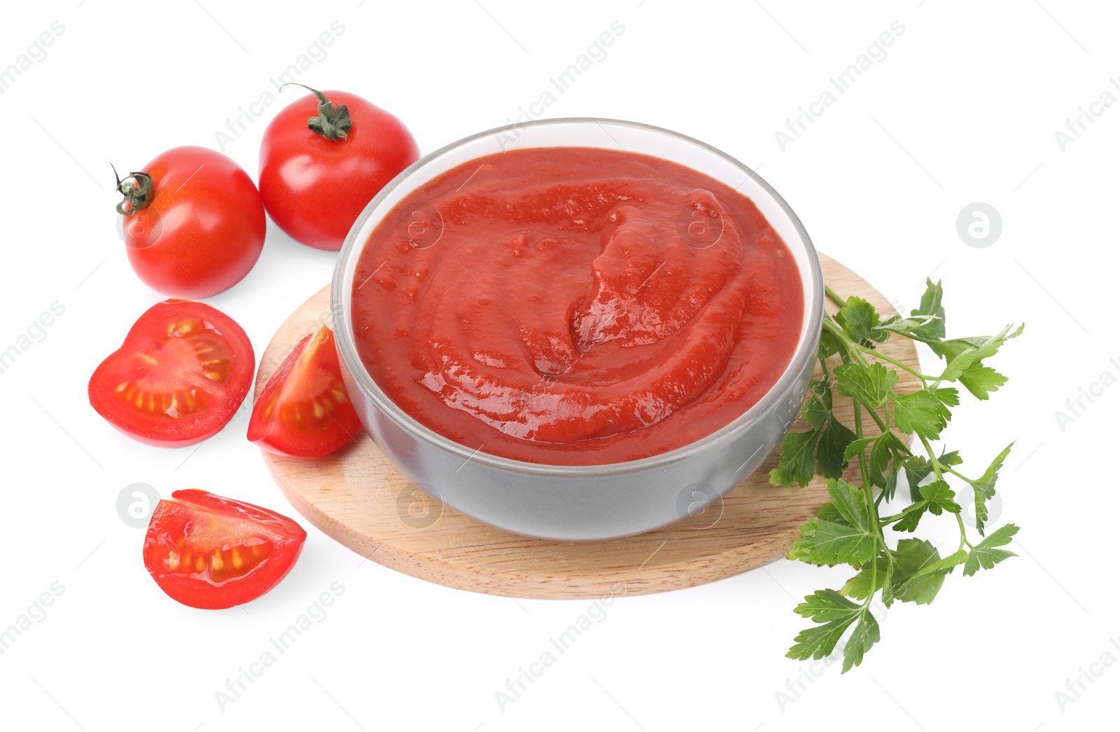 Photo of Organic ketchup in bowl, fresh tomatoes and parsley isolated on white. Tomato sauce