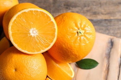 Fresh oranges with leaves on wooden table, closeup