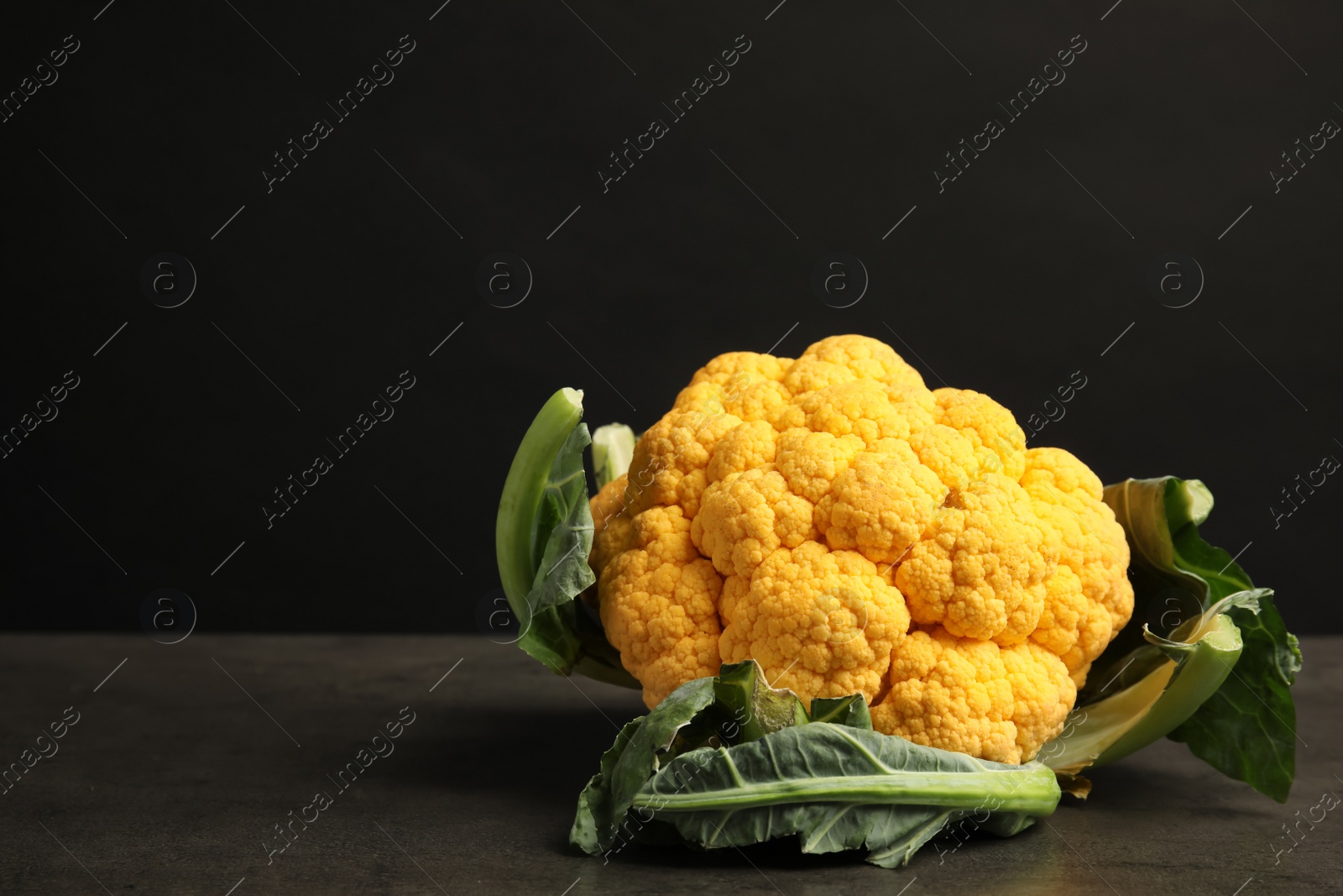 Photo of Yellow cauliflower cabbage on table against black background. Healthy food