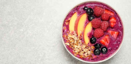 Healthy breakfast with delicious acai smoothie in bowl on light grey table, top view. Space for text