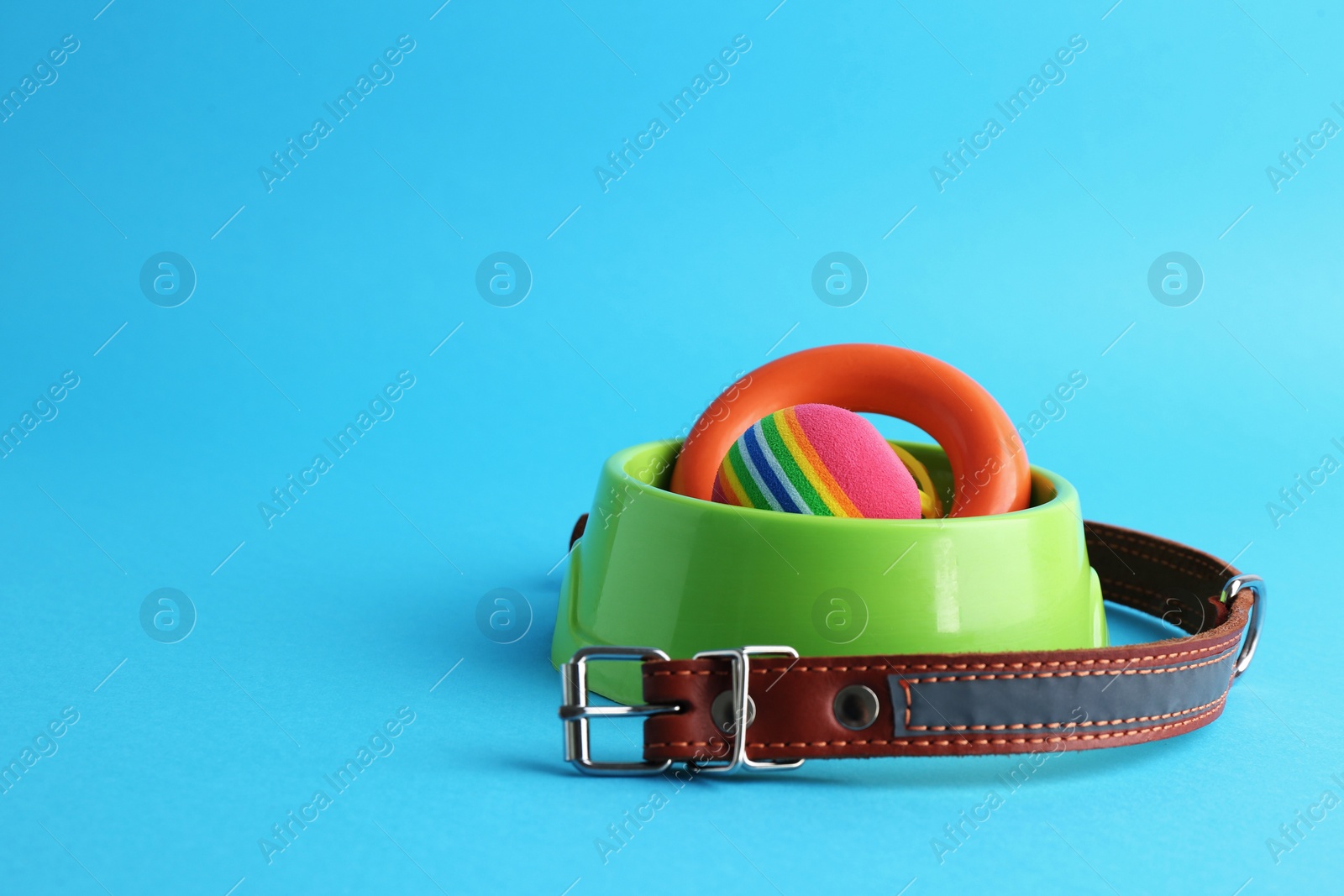 Photo of Pet toys, collar and feeding bowl on light blue background, space for text