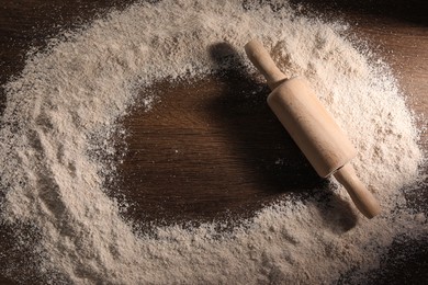 Frame of flour and rolling pin on wooden table, top view. Space for text