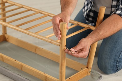Photo of Man with self-tapping screw assembling furniture on floor, closeup
