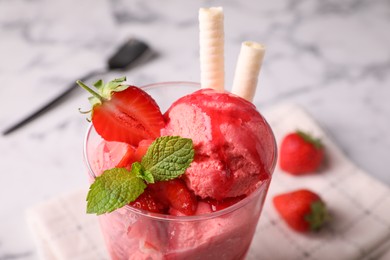Photo of Tasty strawberry ice cream with fresh berries and wafer rolls in glass dessert bowl on table, closeup
