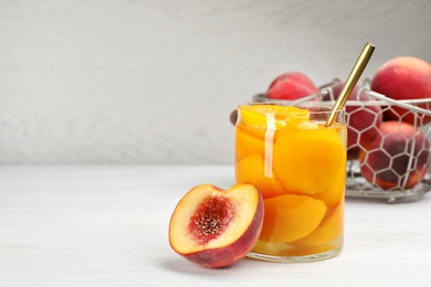 Photo of Glass jar with conserved peach halves on table. Space for text