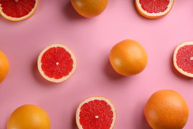Photo of Cut and whole ripe grapefruits on pink background, flat lay