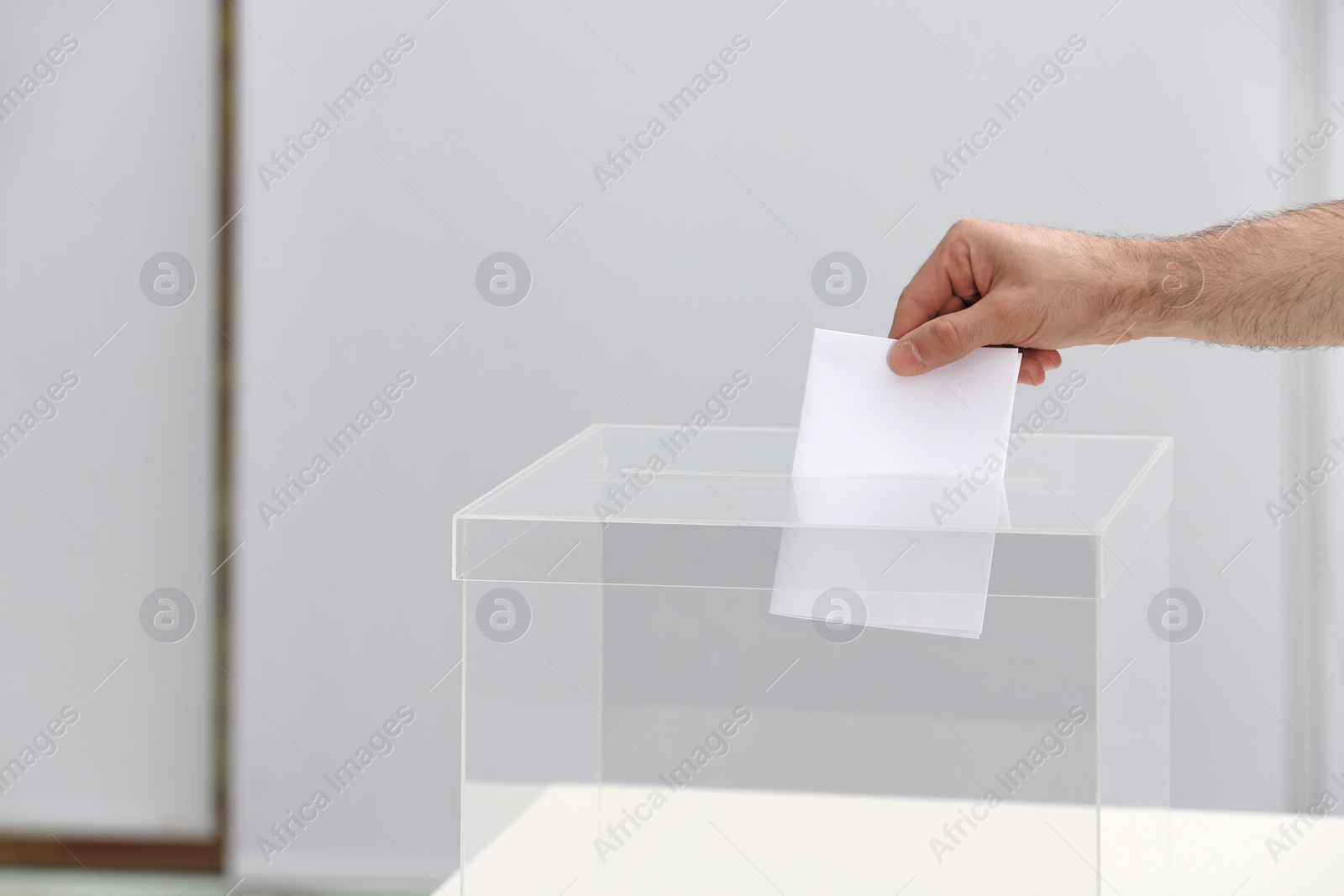 Photo of Man putting his vote into ballot box at polling station, closeup. Space for text