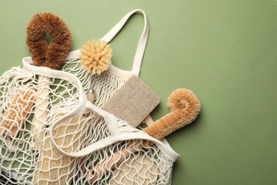 Photo of Bag with eco friendly products on green background, flat lay. Conscious consumption