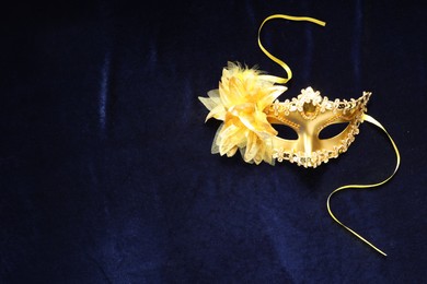 Photo of Theater arts. Golden venetian carnival mask on blue fabric, top view. Space for text