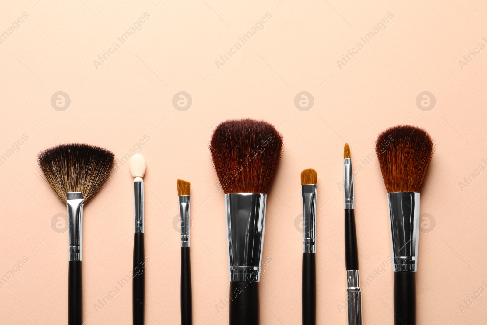 Photo of Different makeup brushes on light beige background, flat lay . Space for text