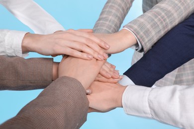 Photo of Women holding hands together on light blue background, closeup