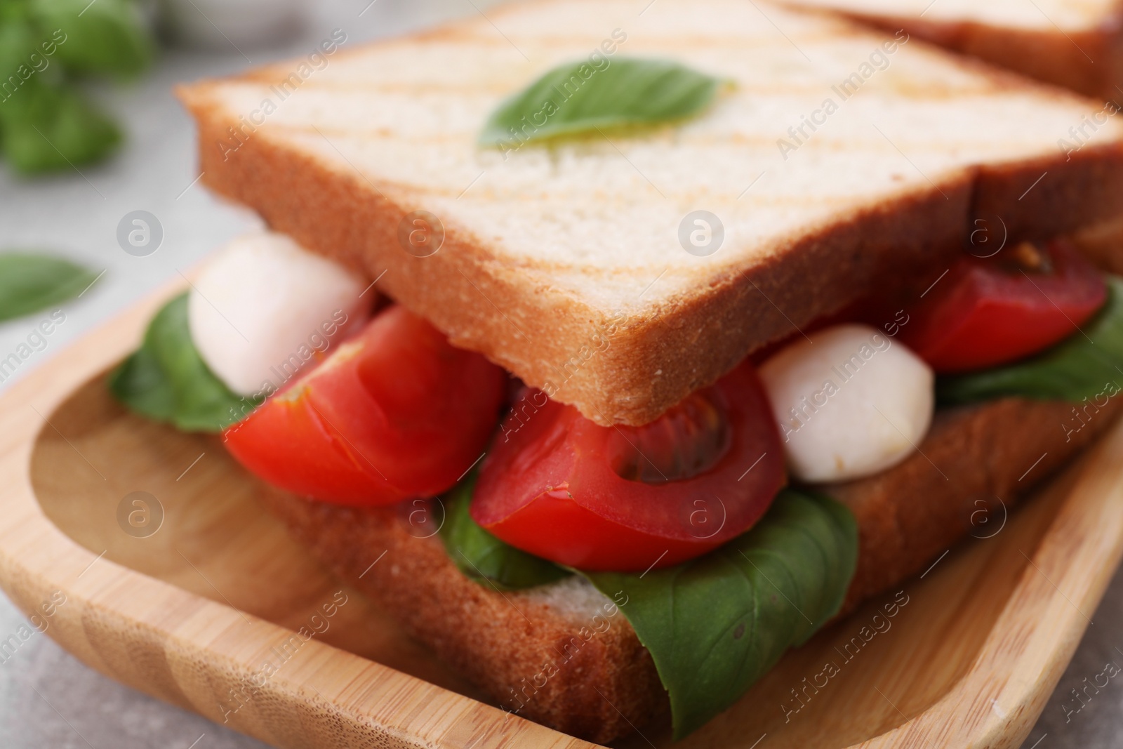 Photo of Delicious Caprese sandwich with mozzarella, tomatoes, basil and pesto sauce on table, closeup