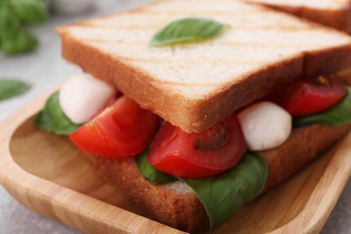 Photo of Delicious Caprese sandwich with mozzarella, tomatoes, basil and pesto sauce on table, closeup