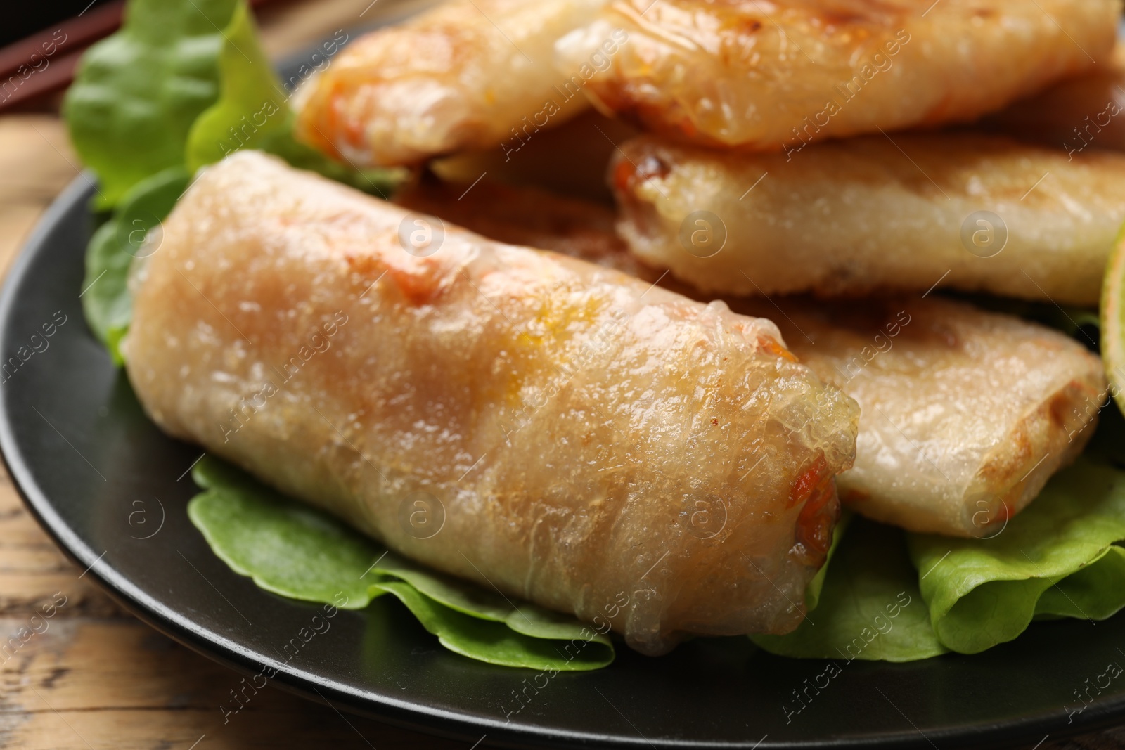 Photo of Tasty fried spring rolls and lettuce on table, closeup