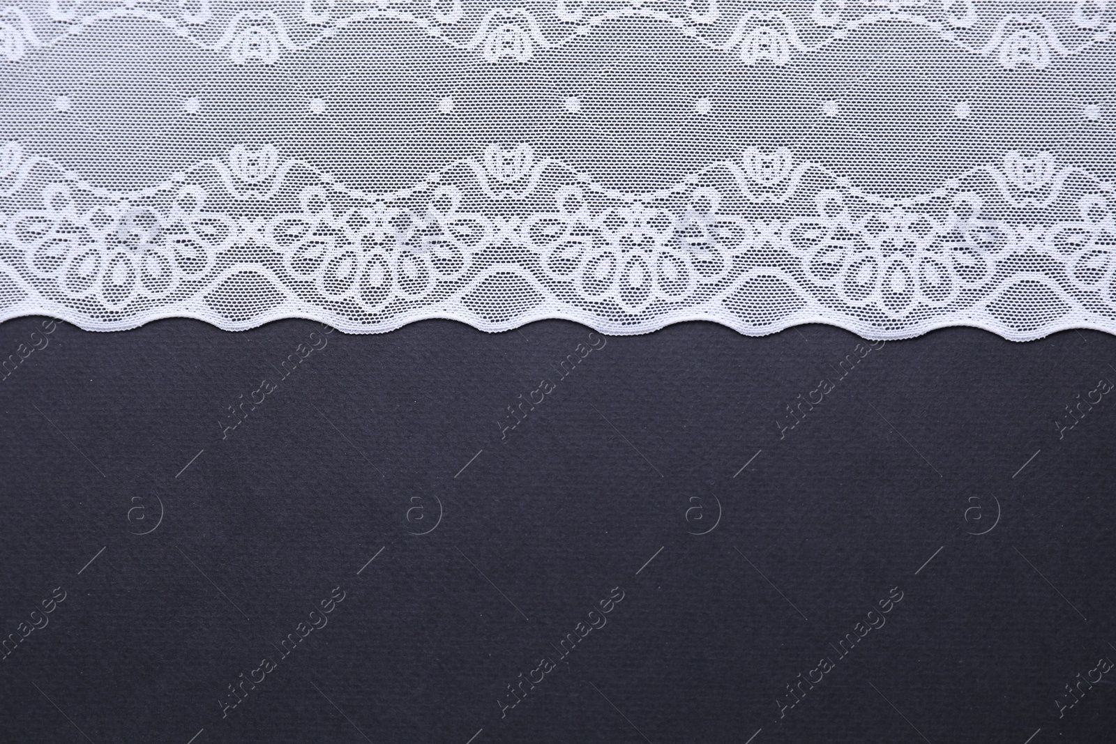 Photo of White lace on black background, top view. Space for text