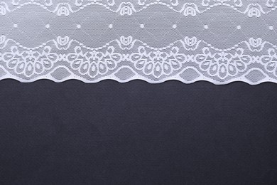 Photo of White lace on black background, top view. Space for text