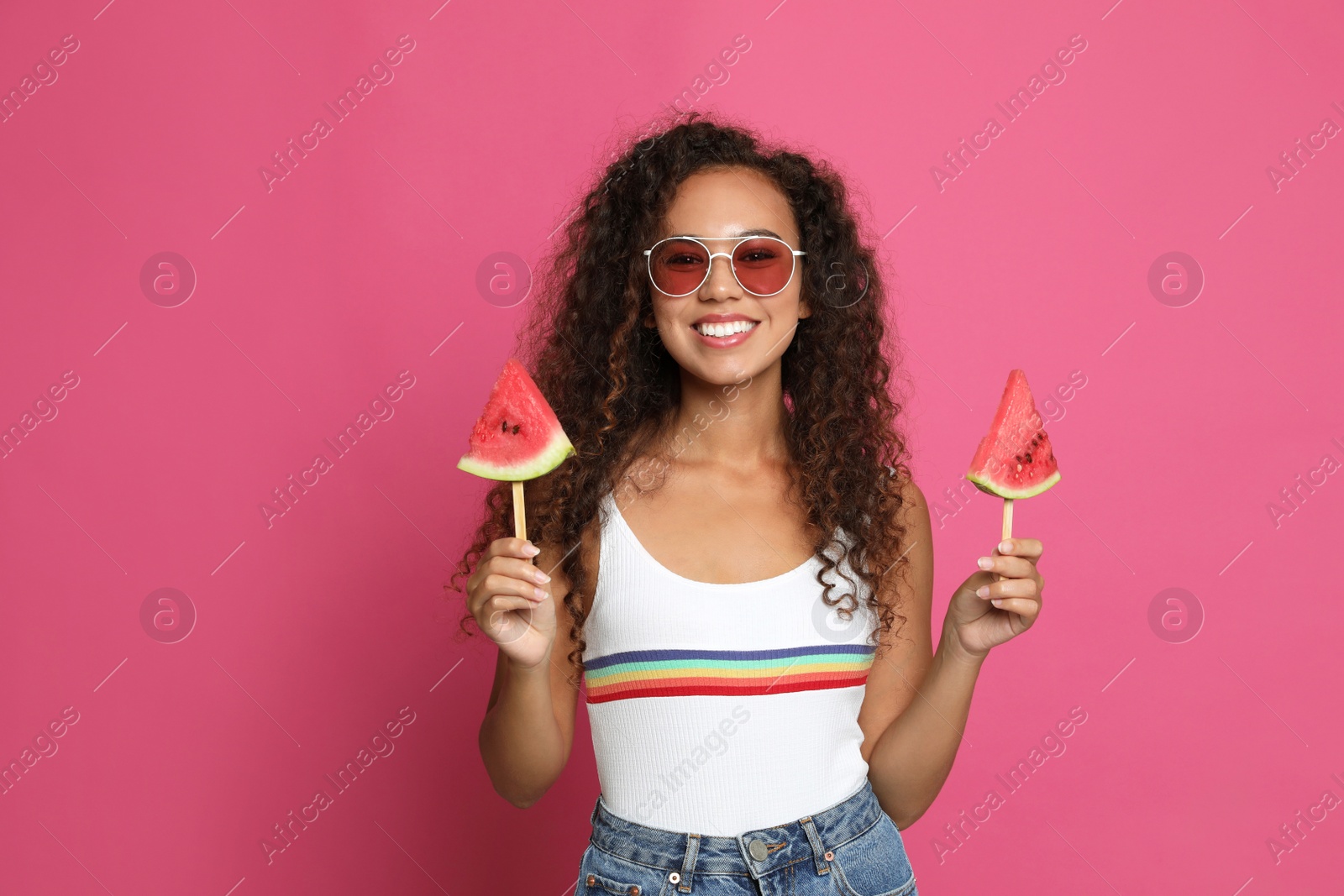 Photo of Beautiful young African American woman with pieces of watermelon on crimson background