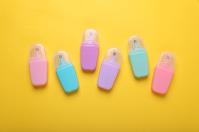 Many colorful markers on yellow background, flat lay