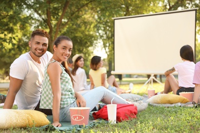 Photo of Young couple with popcorn watching movie in open air cinema. Space for text