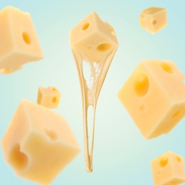 Pieces of cheese falling on light blue background