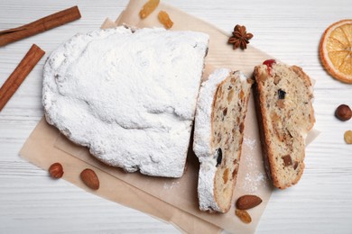 Photo of Traditional Christmas Stollen with icing sugar on white wooden table, flat lay