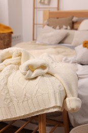 Photo of Warm sweater near bed in room. Home textile