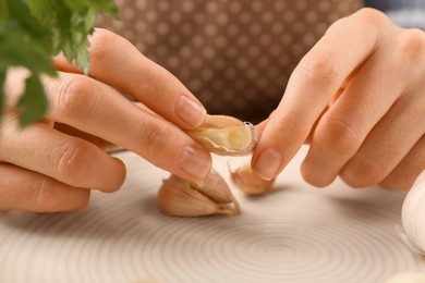 Photo of Woman peeling fresh garlic at table, selective focus