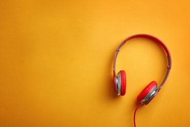 Photo of Stylish headphones on color background, top view. Space for text