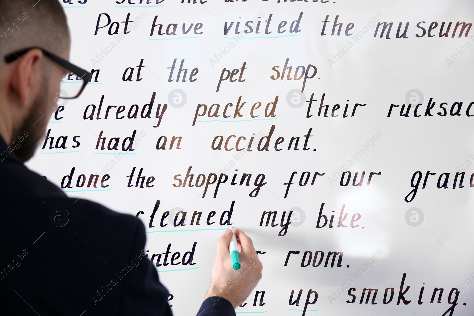 Photo of English teacher underlining word on whiteboard at lesson, closeup