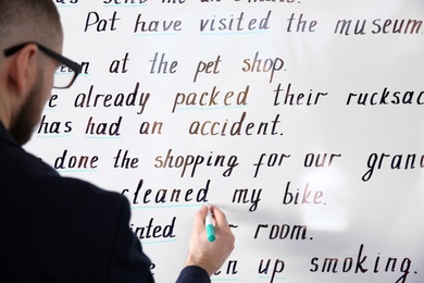 Photo of English teacher underlining word on whiteboard at lesson, closeup